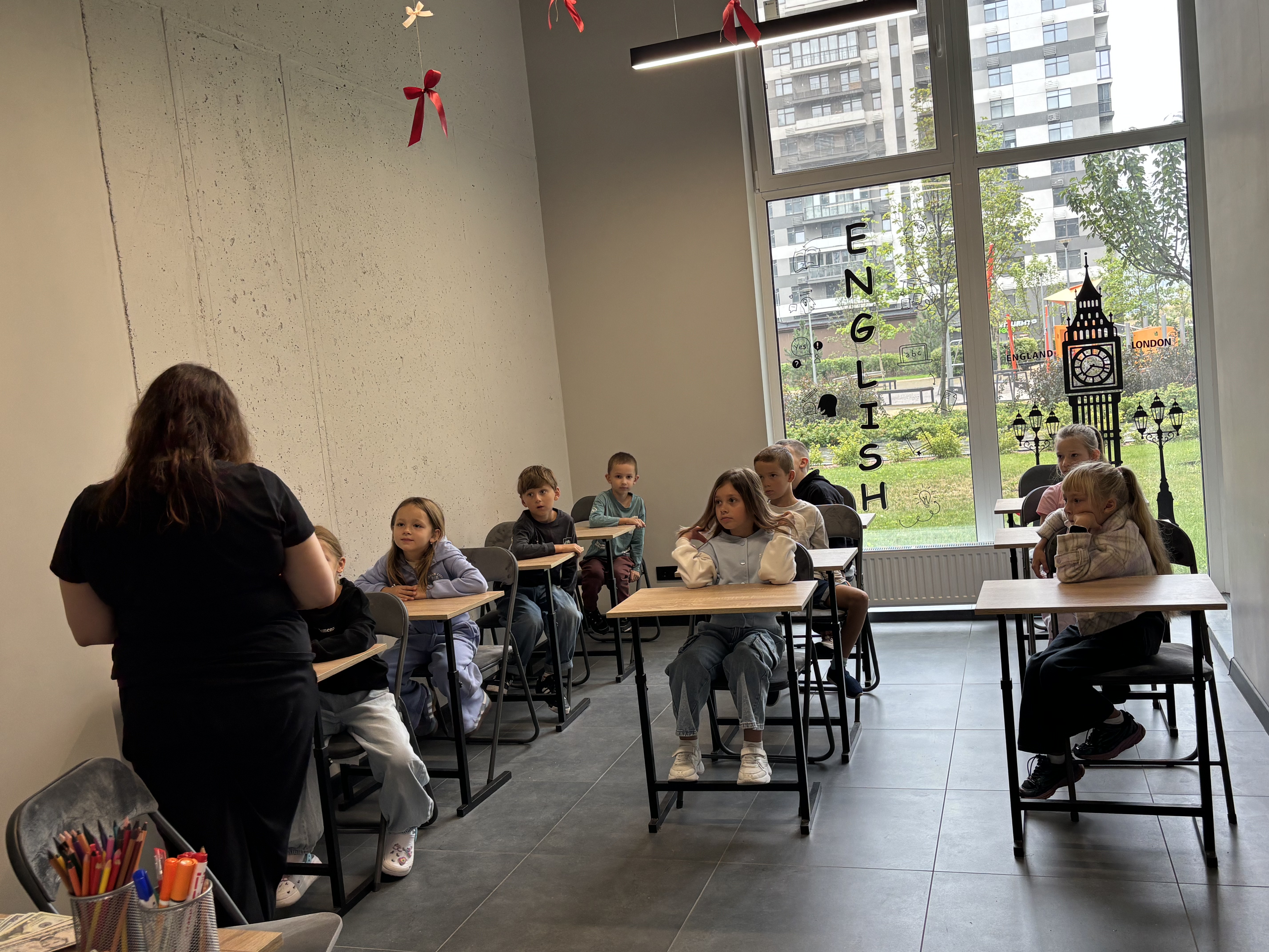 Учні слухають викладачку у світлій класній кімнаті Winglish School
